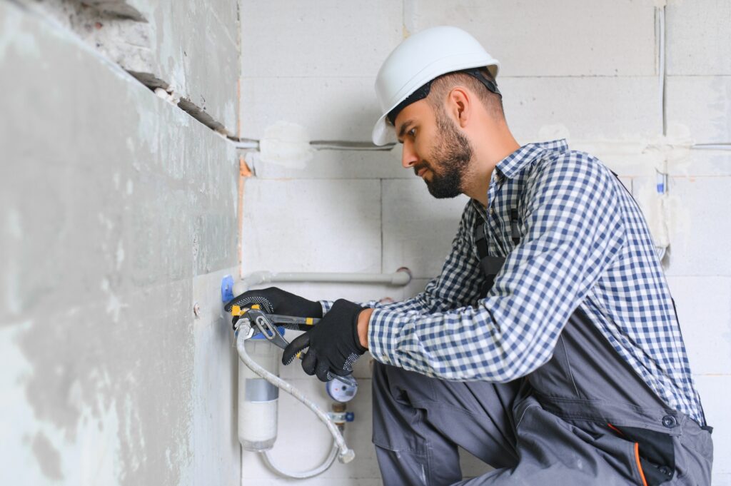 Horizontal snapshot of young plumber working with grey sewer pipes