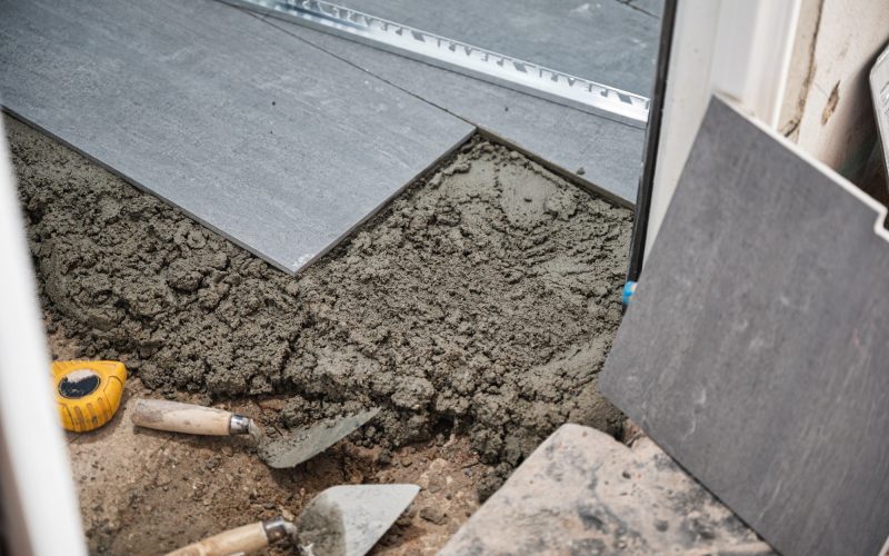 Contractor working with granite tile flooring with cement and tools in bathroom