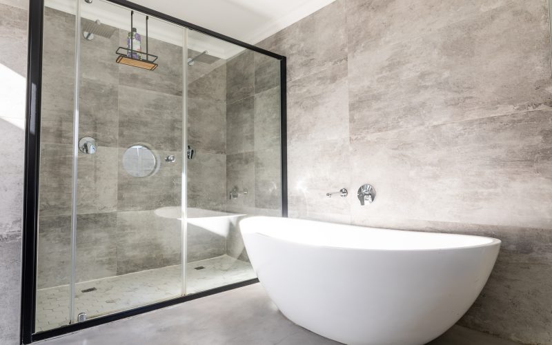 Empty bathtub by modern shower in bathroom at home