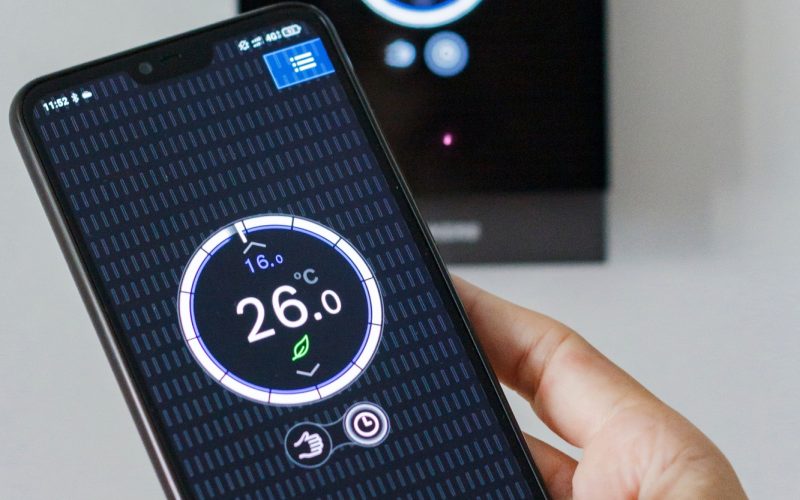 Female hands controlling via app on mobile phone the temperature in a thermostat at home, wireless